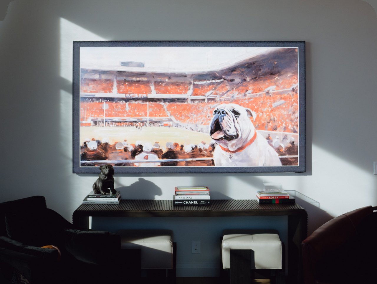 A luxury living room with a large wall display showing a football game, lit by afternoon sun